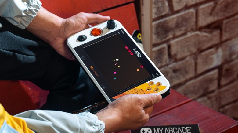 A pair of hands holding the My Arcade Atari Gamestation Go