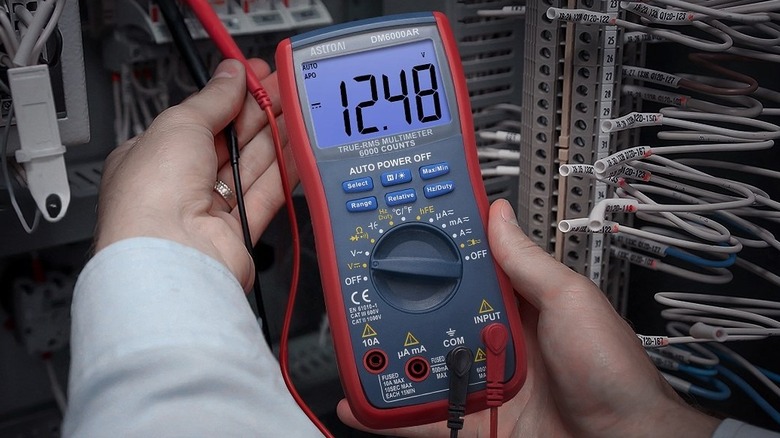 AstroAI Digital Multimeter held in hand testing voltage