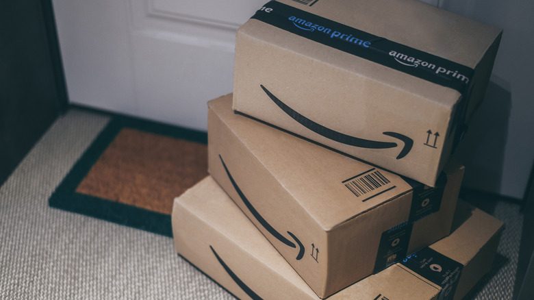 A stack of Amazon boxes outside a door.