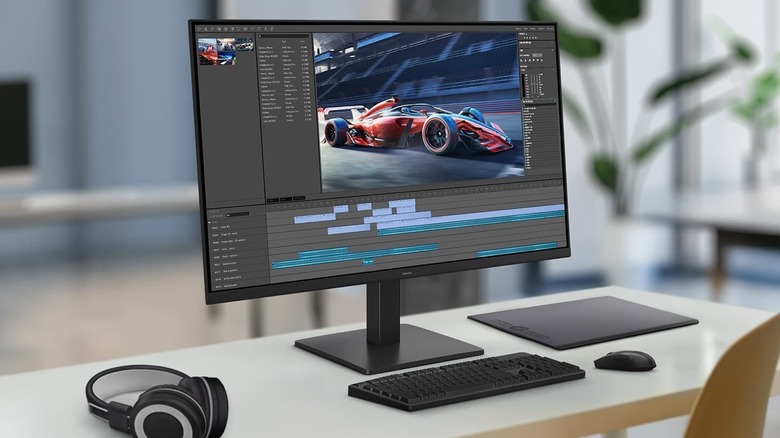 The Samsung S32GF monitor on a work desk with a computer accessories around