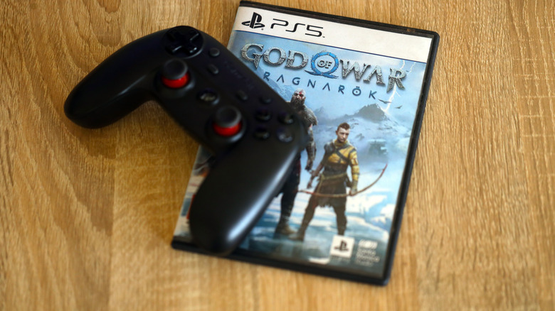 A copy of God of War: Ragnarok for the PlayStation 5 under a game controller.