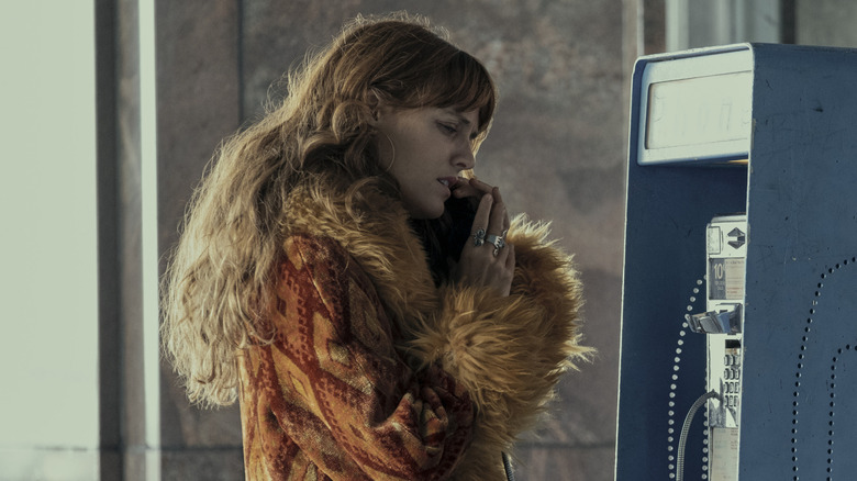 Daisy Jones speaking on a payphone while wearing a patterned coat in Daisy Jones & the Six (2023)