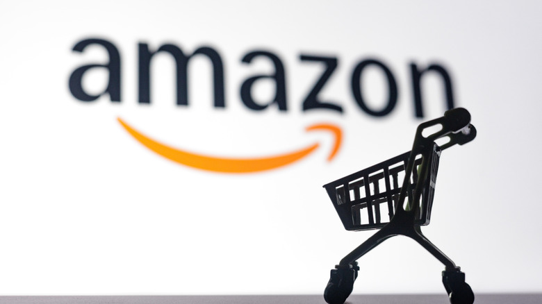 A shopping cart in front of a large Amazon logo