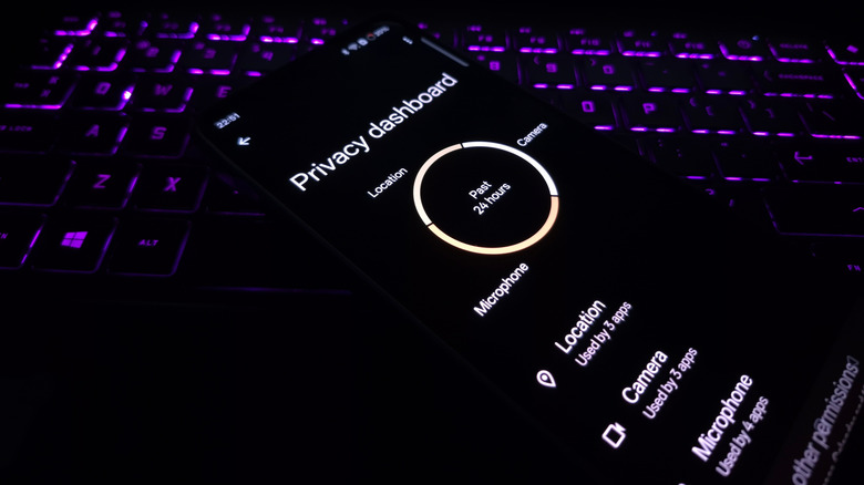 Android phone showing privacy dashboard placed on a laptop with backlit keyboard