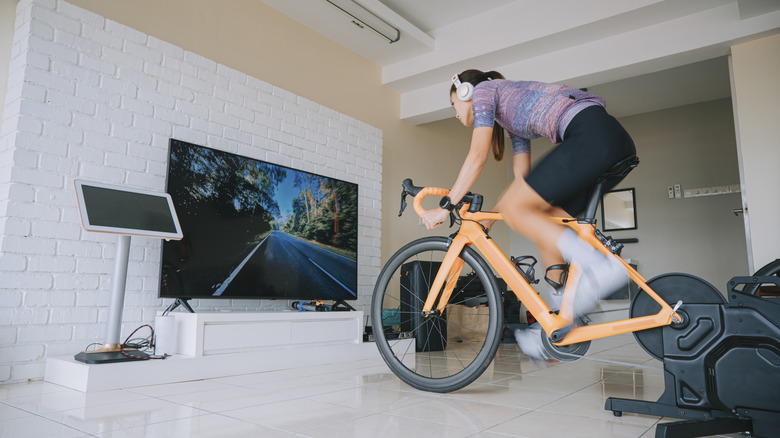 Asian Chinese woman cycling with stationary bicycle trainer at home