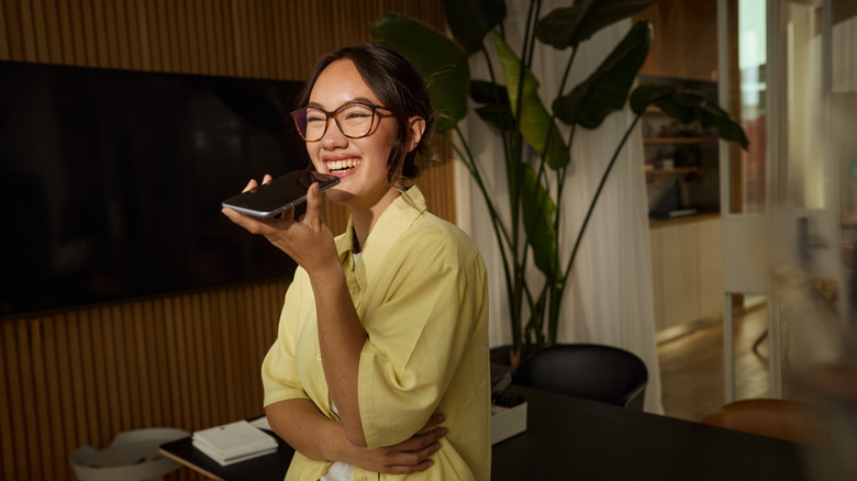A woman smiling while speaking to her phone's mic