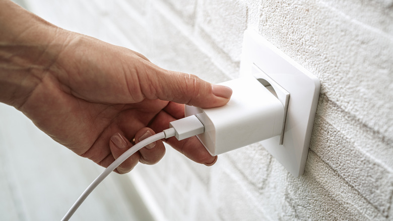 A USB-A charging brick being plugged into a wall's outlet