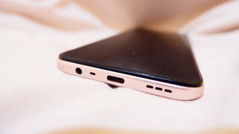 A cellphone that appears to be laying on a blanket, the phone is displaying its speaker, USB-C input, and 3.5mm audio input that's on the bottom of the device