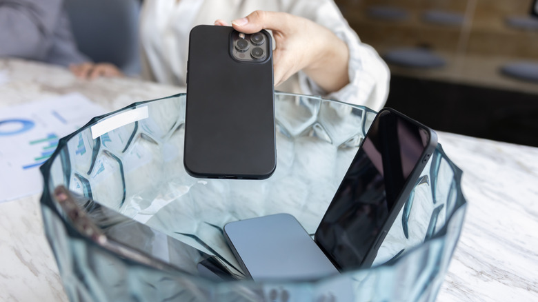 Putting phone inside a glass container with other phones