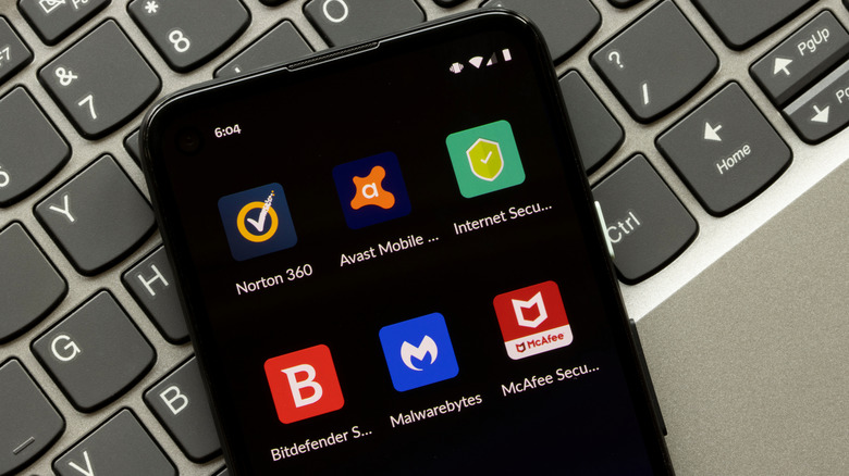 Security apps on phone screen with black background, laying on top of keyboard