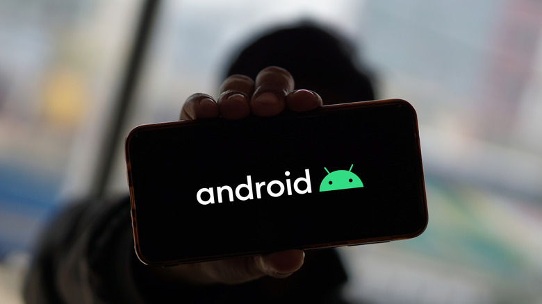 Person holding a phone with Android logo displayed