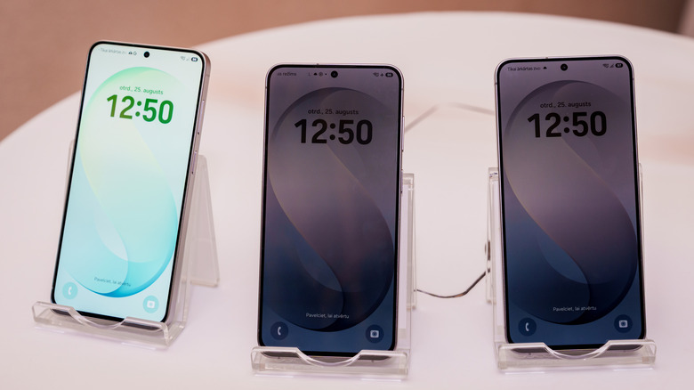 Trio of Samsung Galaxy S26 FE smartphones positioned on stands.
