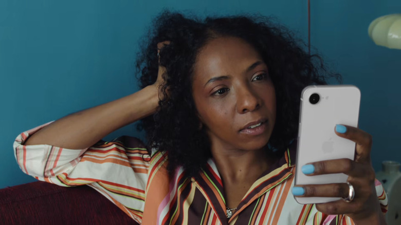 A woman with an almost frustrated expression looking at an iPhone 17e.