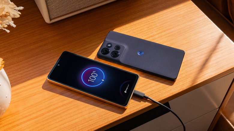 The Motorola Moto G Power charging via a USB cable on a wooden table