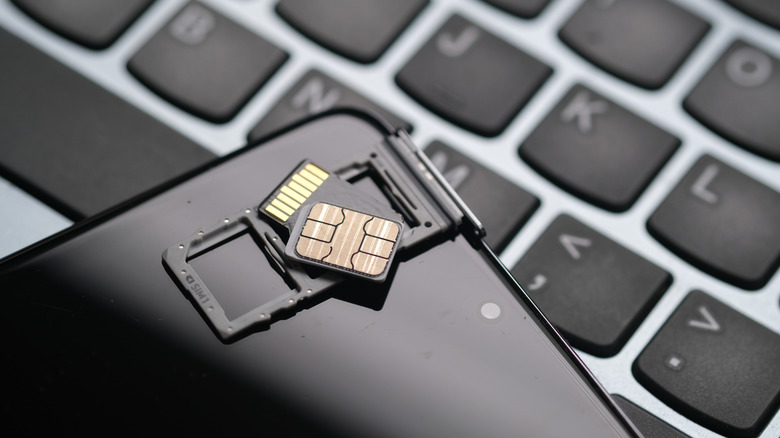 A SIM card and microSD card on a SIM tray placed atop a smartphone