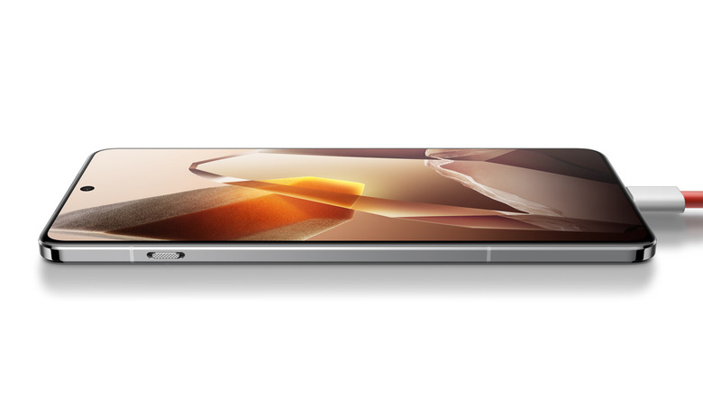 OnePlus 13 lay down on a white background on charge, showcasing an abstract crystal image.