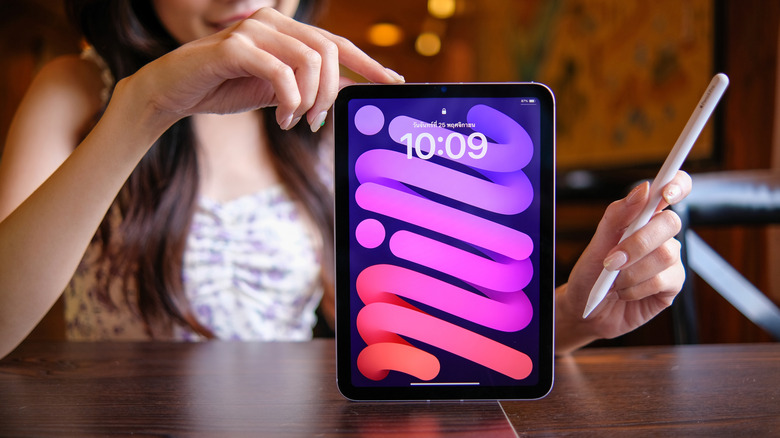 An iPad mini 7 user carrying an Apple Pencil in her hand