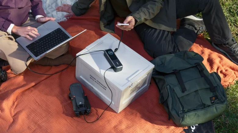 Two people on a picnic mat while using Anker laptop power bank