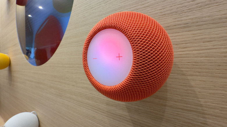 An orange Apple HomePod speaker mounted on a wall
