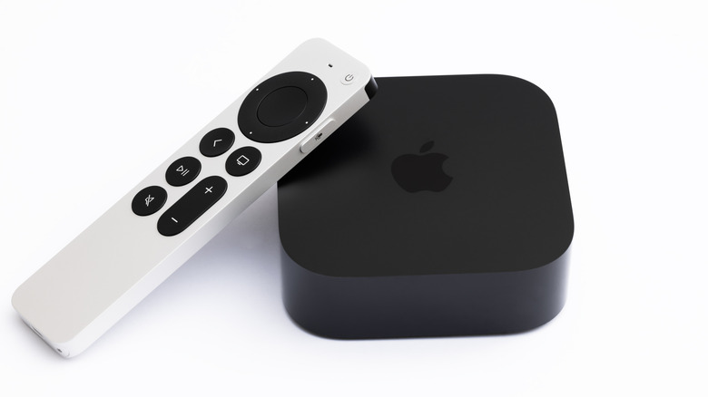 A black Apple TV 4K streaming device with a white remote