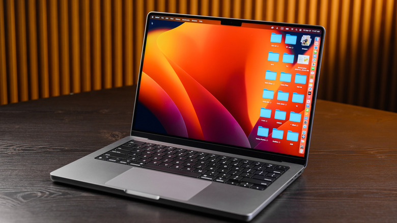 A silver MacBook Pro open to its desktop screen, there are several blue folders on the desktop