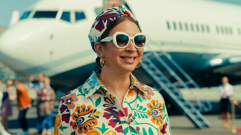 Molly Wells (Maya Rudolph) smiling in front of a private jet in "Loot"