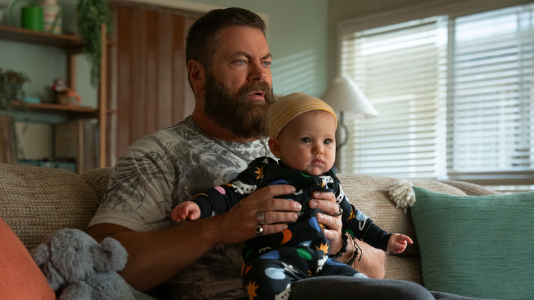 James (Nick Offerman) sitting on a couch holding a baby in "Margo's Got Money Troubles"