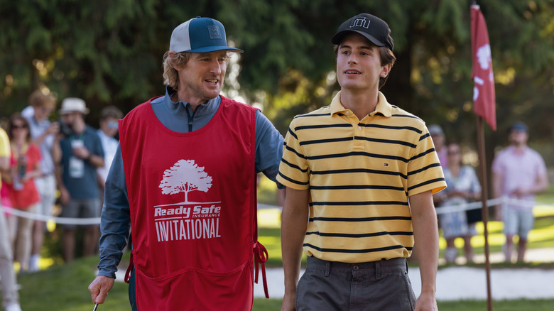 Pryce and Santi smiling and walking on the golfing green in "Stick"