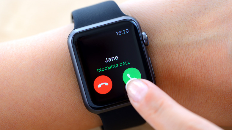 Woman hand touching an Apple Watch displaying an incoming phone call.