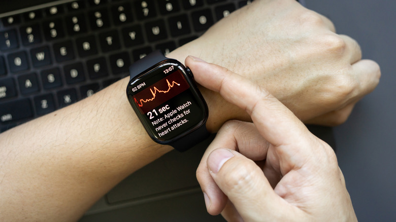 A hand in front of a keyboard running an ECG check from an Apple Watch.
