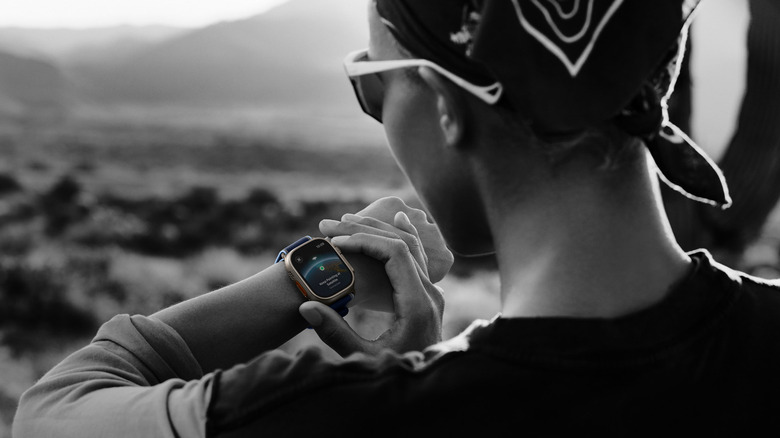 A person wearing an Apple Watch Ultra 3 using the smartwatch's satellite connectivity