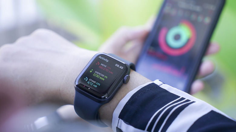 Close-up of an Apple Watch on a wrist with an iPhone in the background, both tracking the user's activity