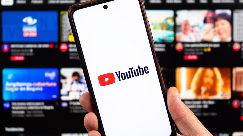 The YouTube logo on a smartphone in front of a TV displaying YouTube content