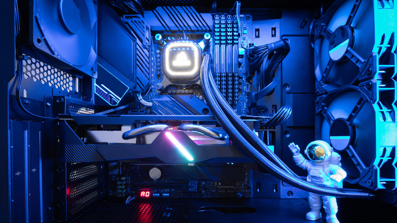 A liquid-cooled gaming PC interior with blue lighting and an astronaut figurine.
