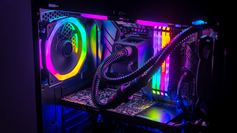 An RGB-lit gaming PC interior with liquid cooling tubes, RAM, and a rear fan.