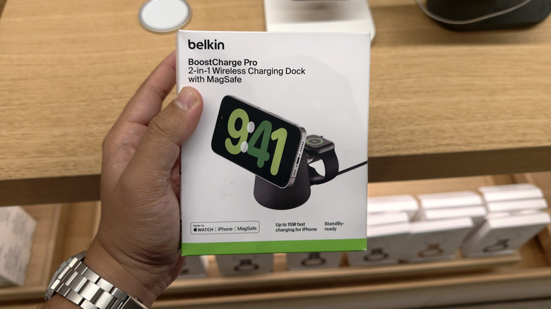 Hand holding a Belkin BoostCharge Pro 2-in-1 Wireless Charging Dock with MagSafe box in a store.
