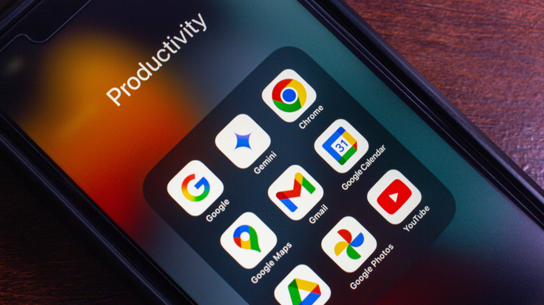 A smartphone sitting on a table, showing an app folder with Google Photos and other apps