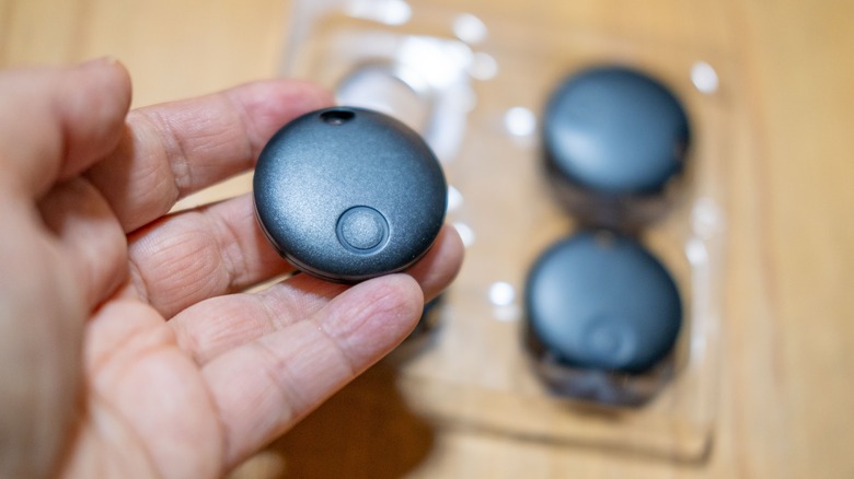 A person holding a smart tracker with other trackers in the background
