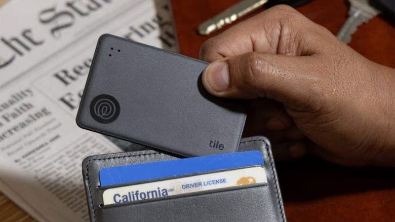 A person placing a Tile Slim in a wallet
