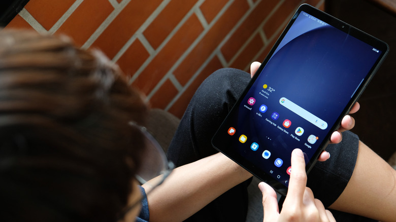 Galaxy Tab A9 held in hand with finger about to touch the screen