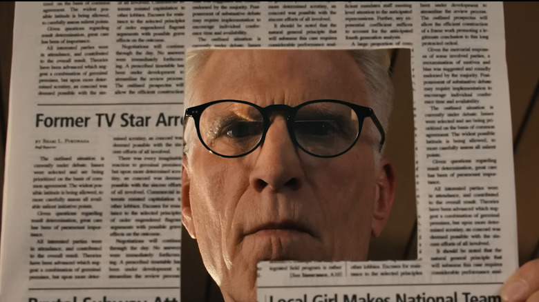 Charles peers through a square cutout in a newspaper in A Man on the Inside