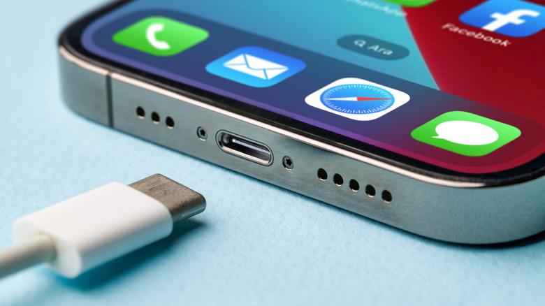 An iPhone with its USB-C port in focus, placed next to a USB-C cable