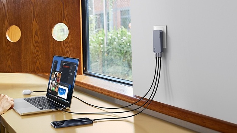 Ugreen Nexode Pro Ultra-Slim Charger plugged into a wall outlet and charging three devices