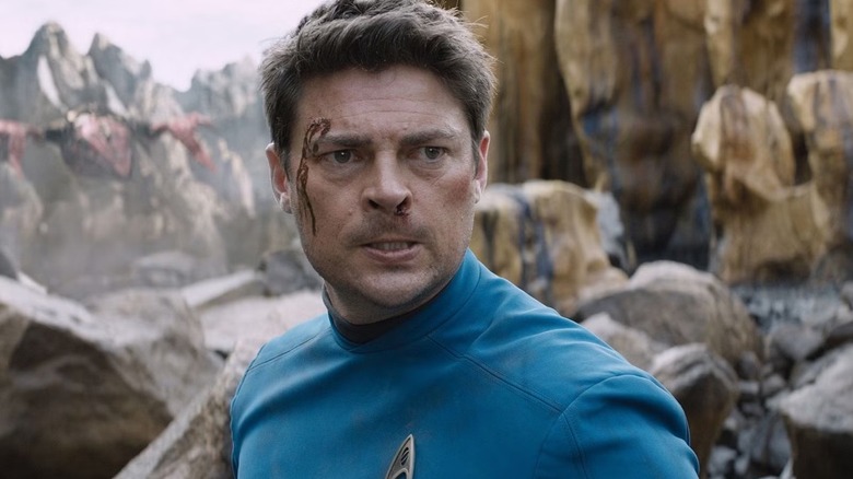 Karl Urban as Dr Henry "Bones" McCoy in Star Trek: Beyond with a cut forehead stood in front of a chasm