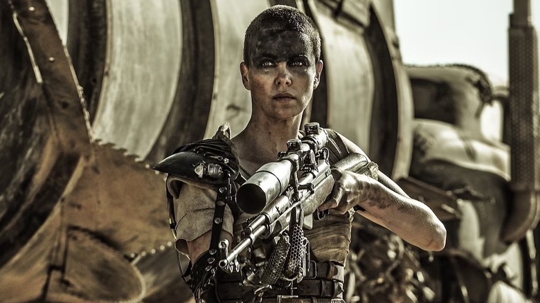 Furiosa (Charlize Theron) holding a sniper rifle in Mad Max: Fury Road