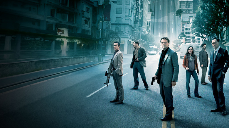 The cast of Inception standing on the street armed with guns