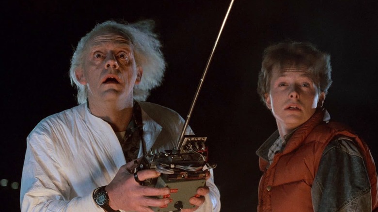 Doc Brown (Christopher Lloyd) holding a remote control stood next to Marty McFly (Michael J. Fox) in Back to the Future