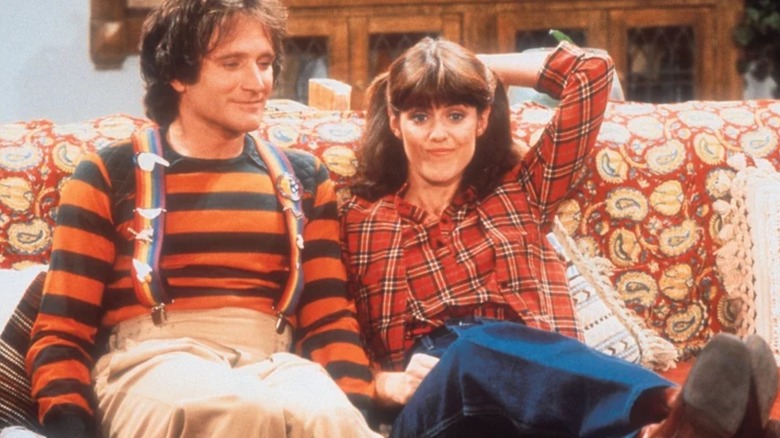 Mork (Robin Williams) and Mindy (Pam Dawber) sitting on the sofa in "Mork & Mindy."