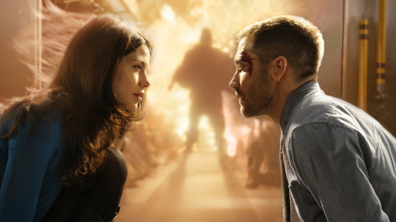 Colter Stevens (Jake Gyllenhaal) looking at Christina Warren (Michelle Monaghan) crouched in front of an explosion in Source Code