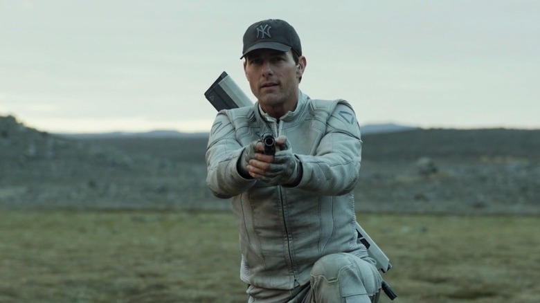 Tom Cruise holding a gun and wearing a baseball hat in Oblivion